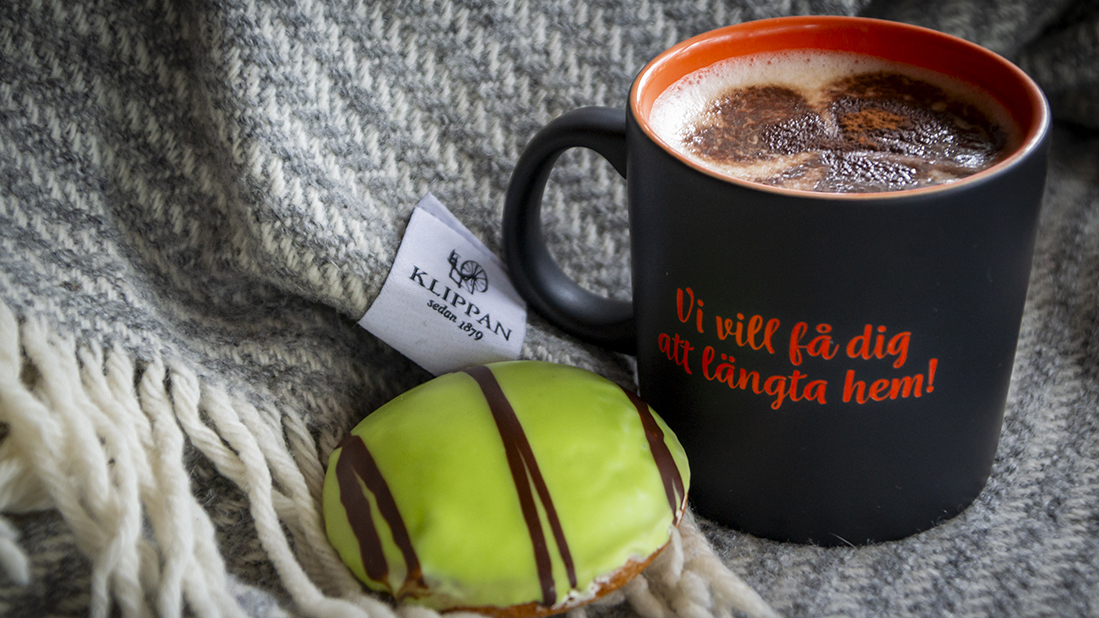En kaka och en mugg kaffe på en Klippan-filt